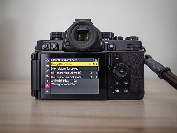 a camera with a menu on the display sits on a wood shelf