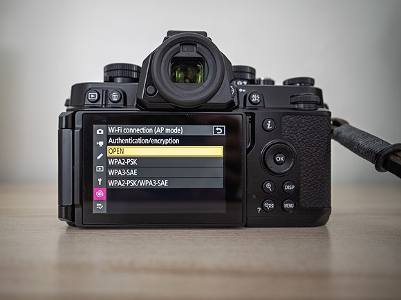 a camera with menu on the display sits on a wood shelf