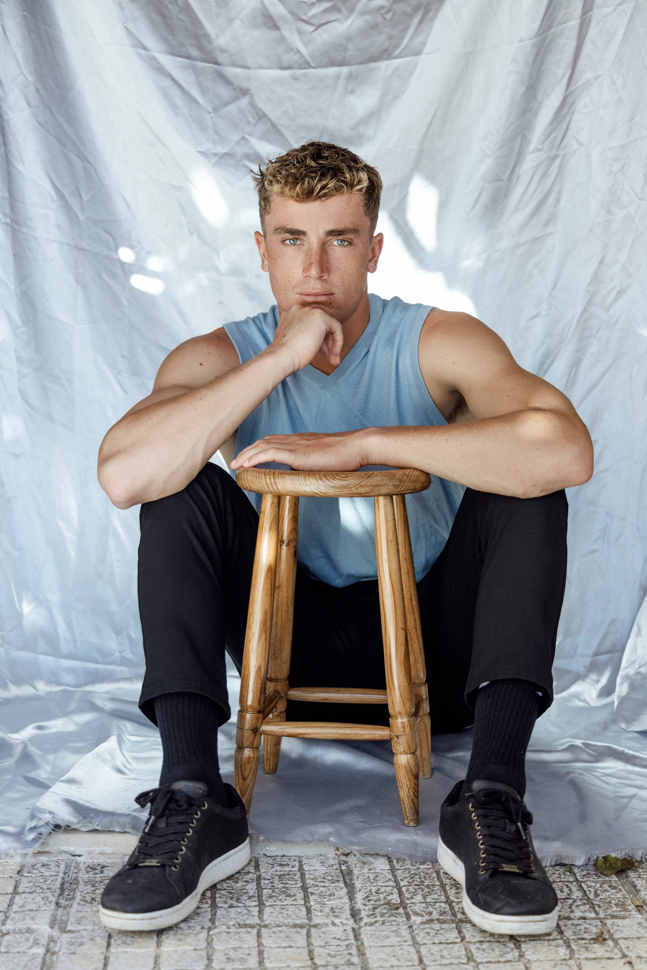 A model posing behind a wooden stool against a studio backdrop, showcasing refined portrait photography by 500px featured photographer David Velez.