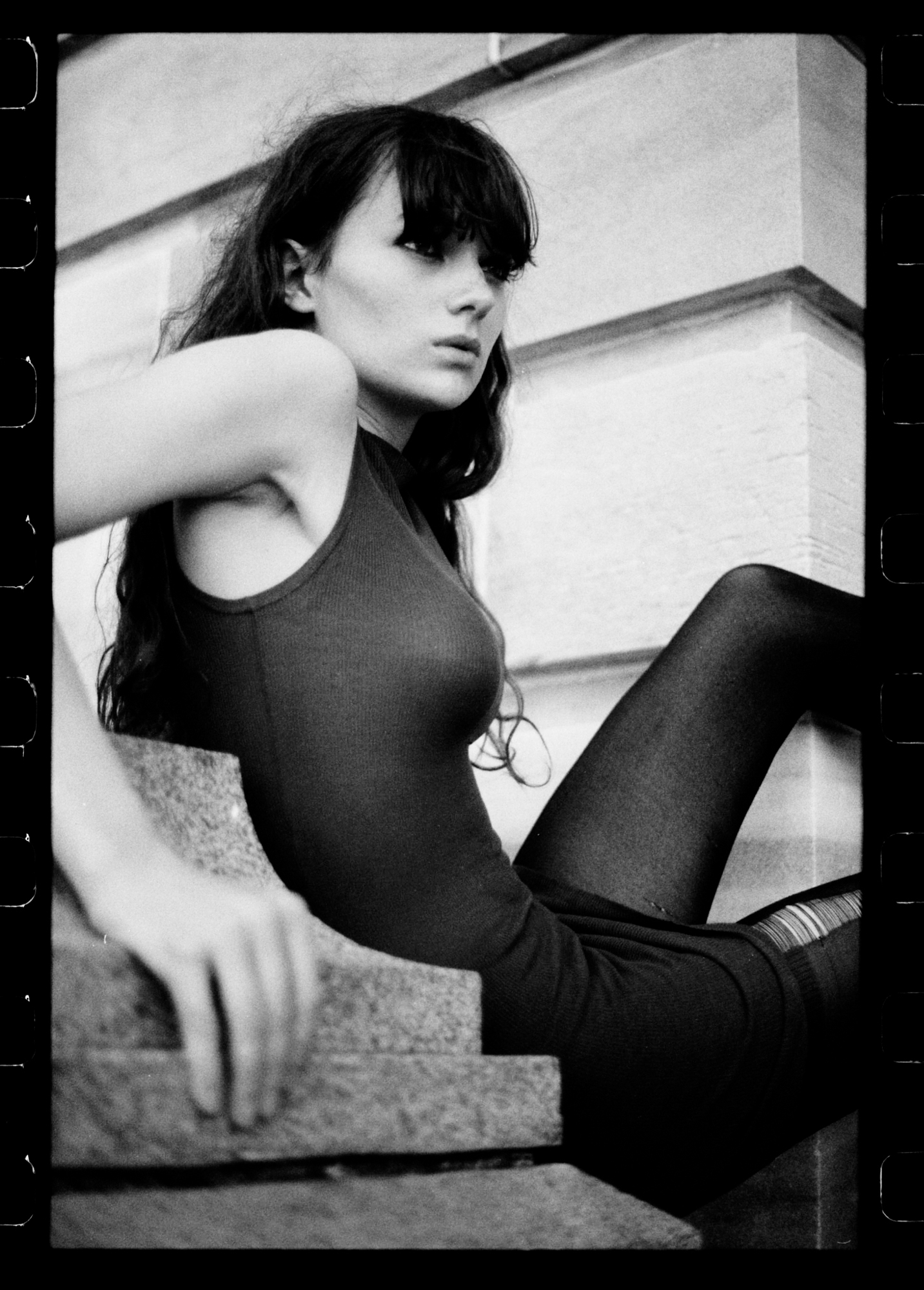 35mm analog film black and white fashion portrait by Holger Nitschke featuring a dark-haired woman reclining on stone steps.