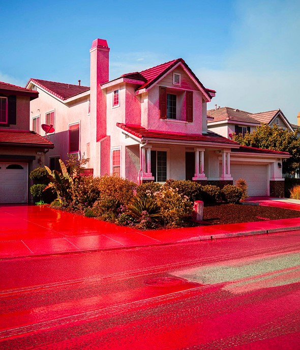 red fire retardant covers the road and houses in a suburban neighborhood