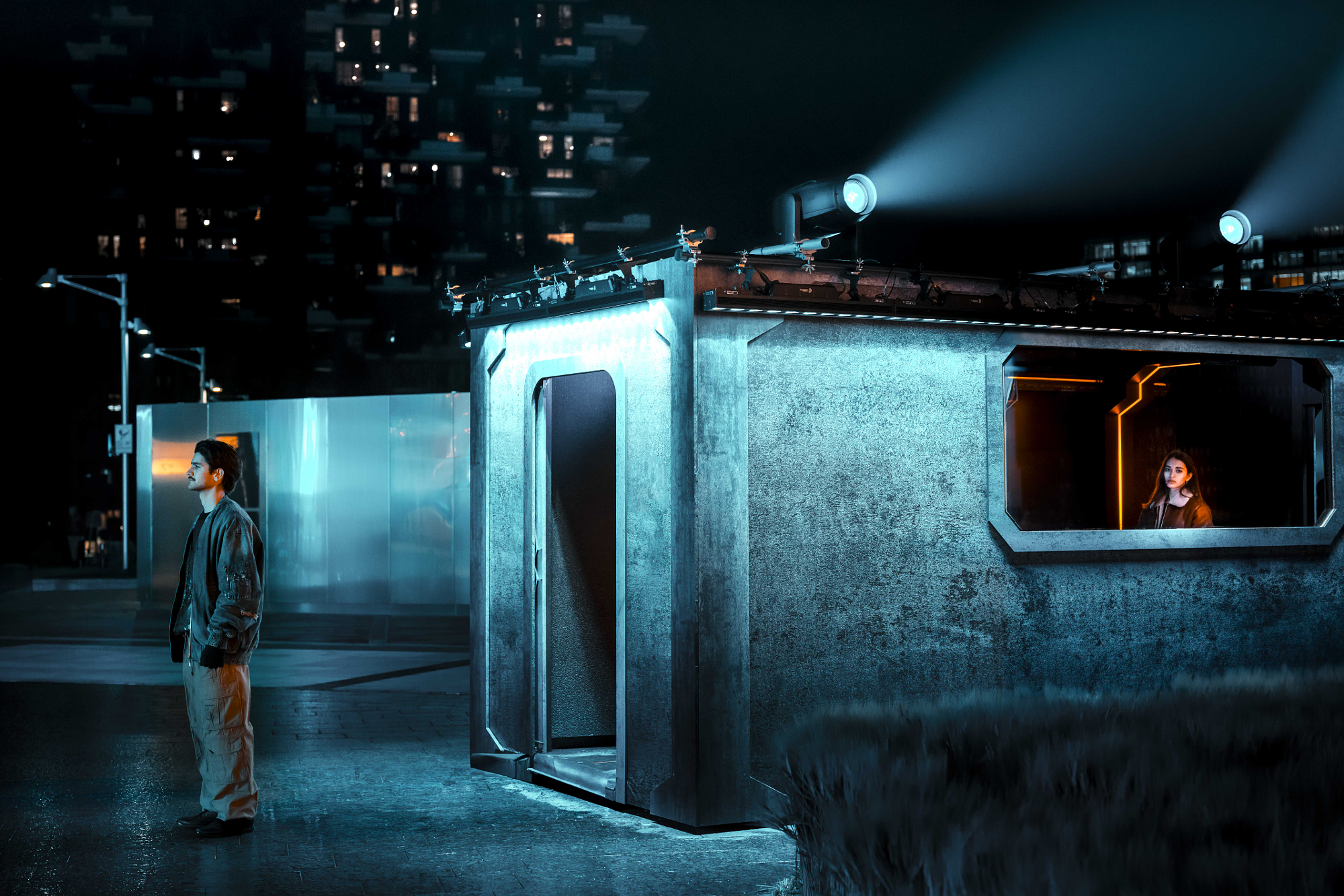 Night scene with cool teal floodlights and a warm orange interior window, showing color temperature contrast in artificial light
