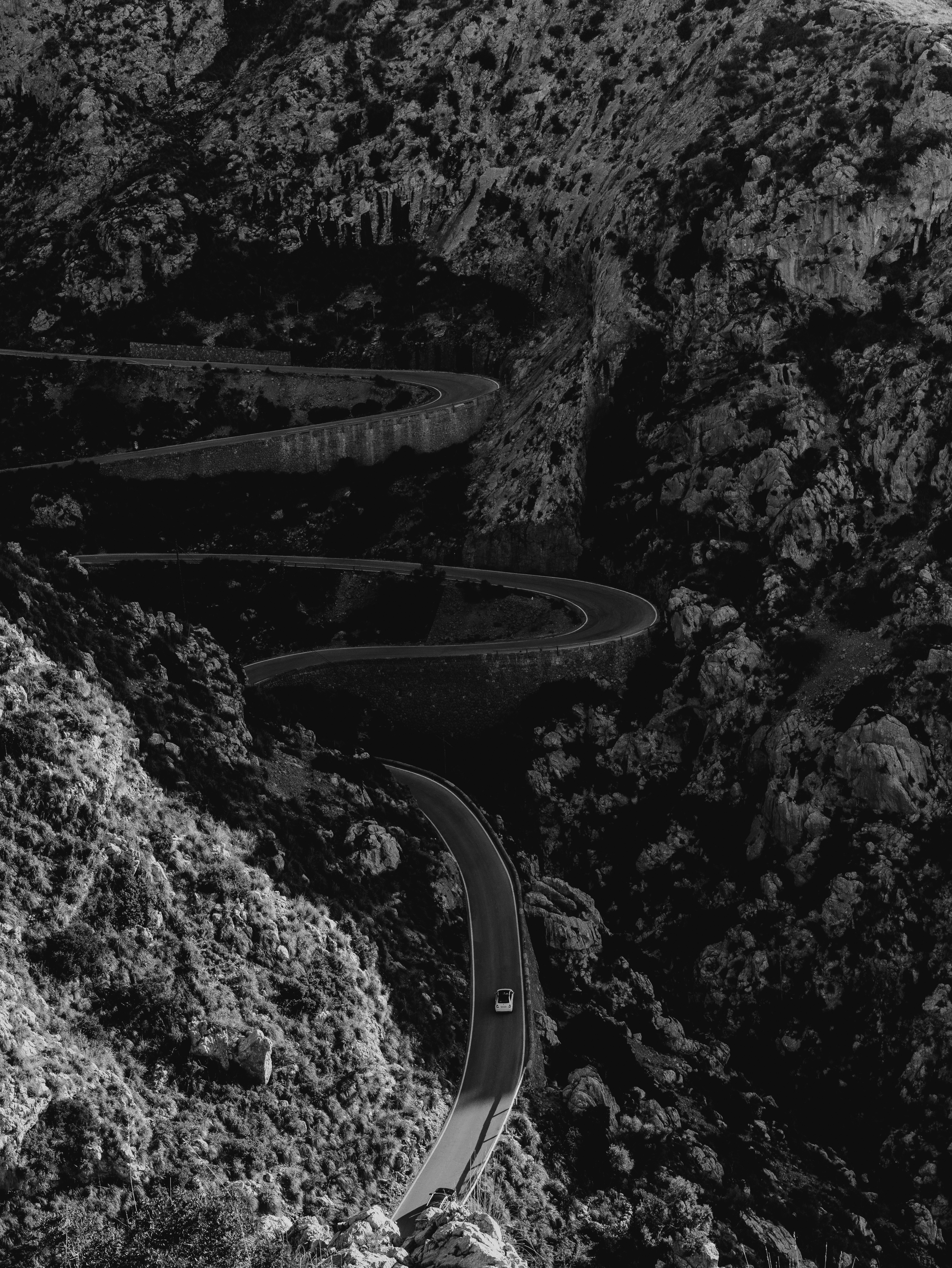 Single car on a hairpin mountain road cut through dark rock, from Eline Deckers's photography.