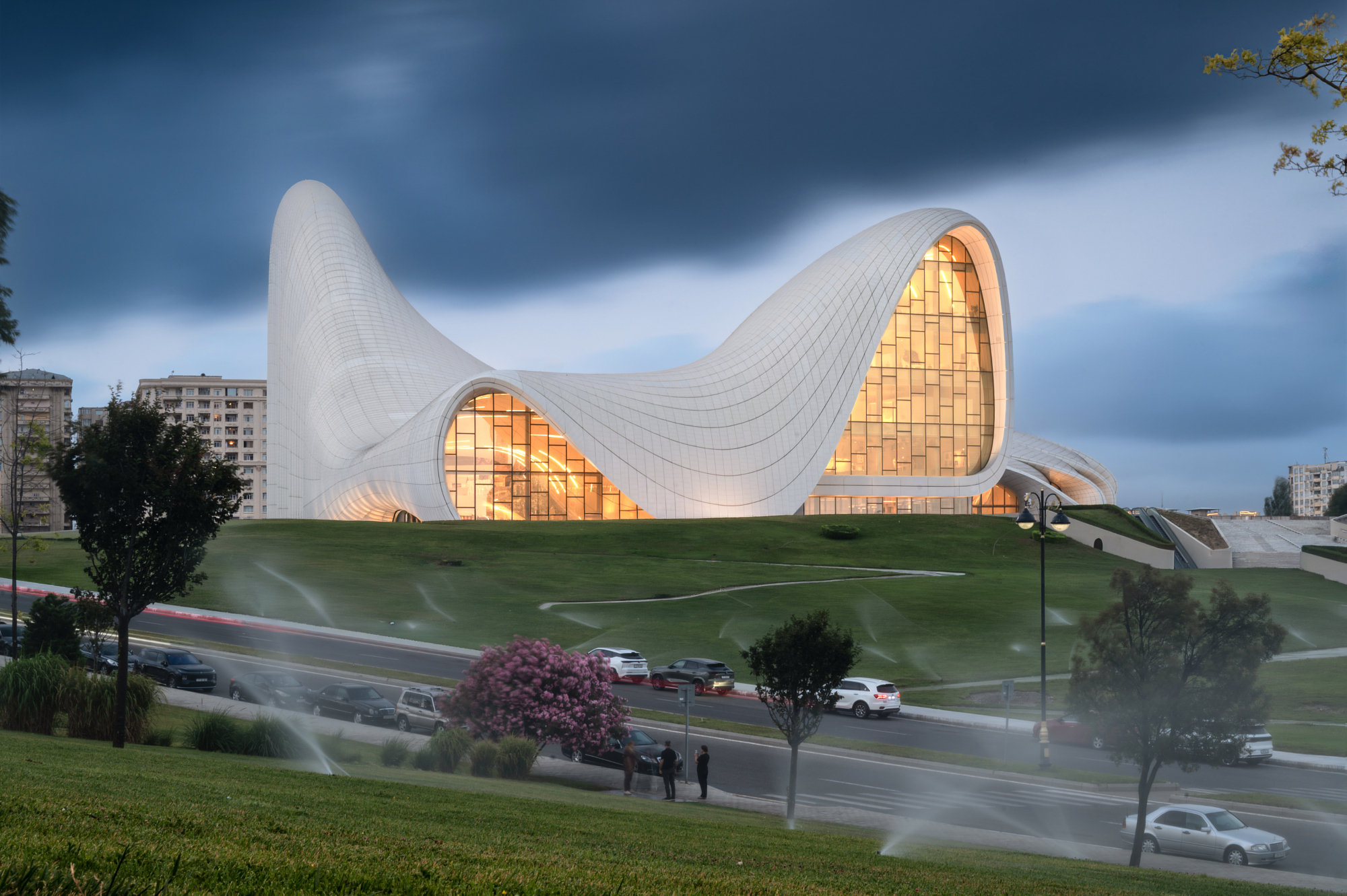 Zaha Hadid's Heydar Aliyev Center in Baku, Azerbaijan, its white curved facade glowing at dusk, from Andrew Shenouda's architectural photography.