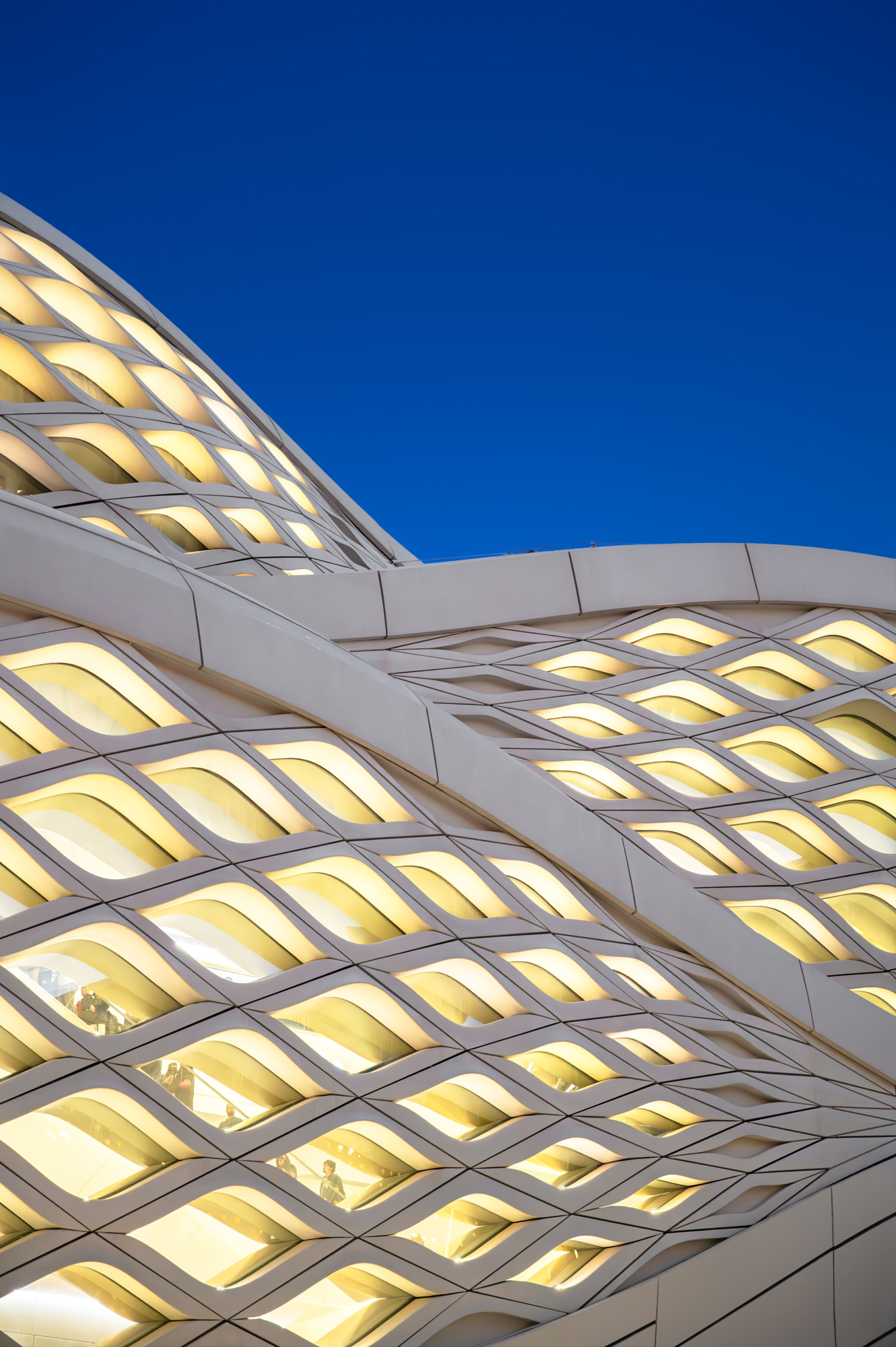 Diamond-lattice facade lit gold at blue hour, an example of parametric design in Andrew Shenouda's architectural photography.